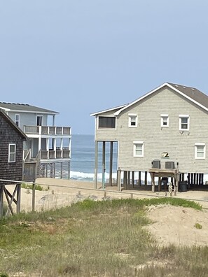 A beachfront property with a large house featuring a balcony and a smaller adjacent building.