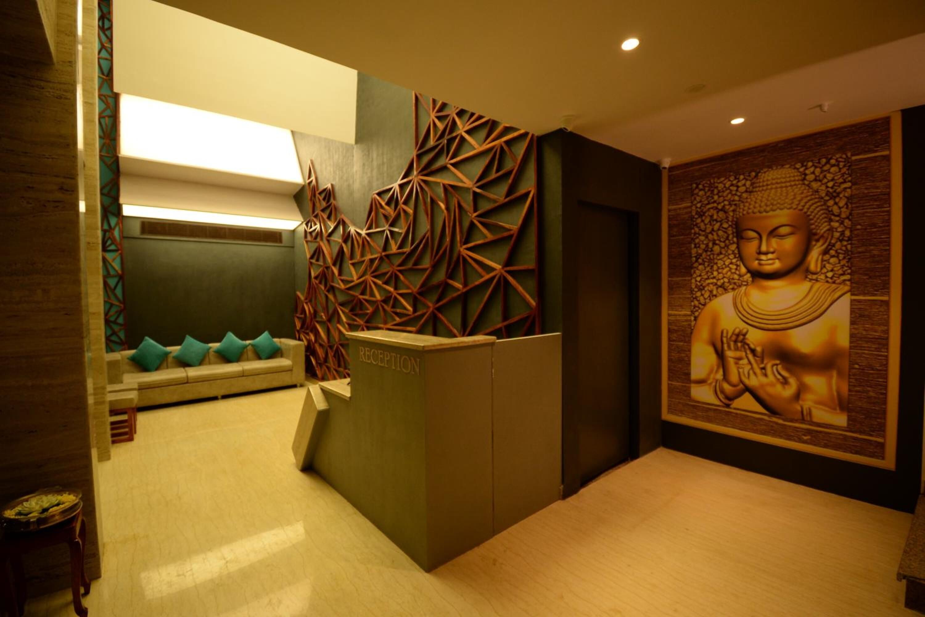 Zona de recepción con un diseño geométrico en la pared, un mural de Buda y un mostrador de recepción con la leyenda 'RECEPTION'.
