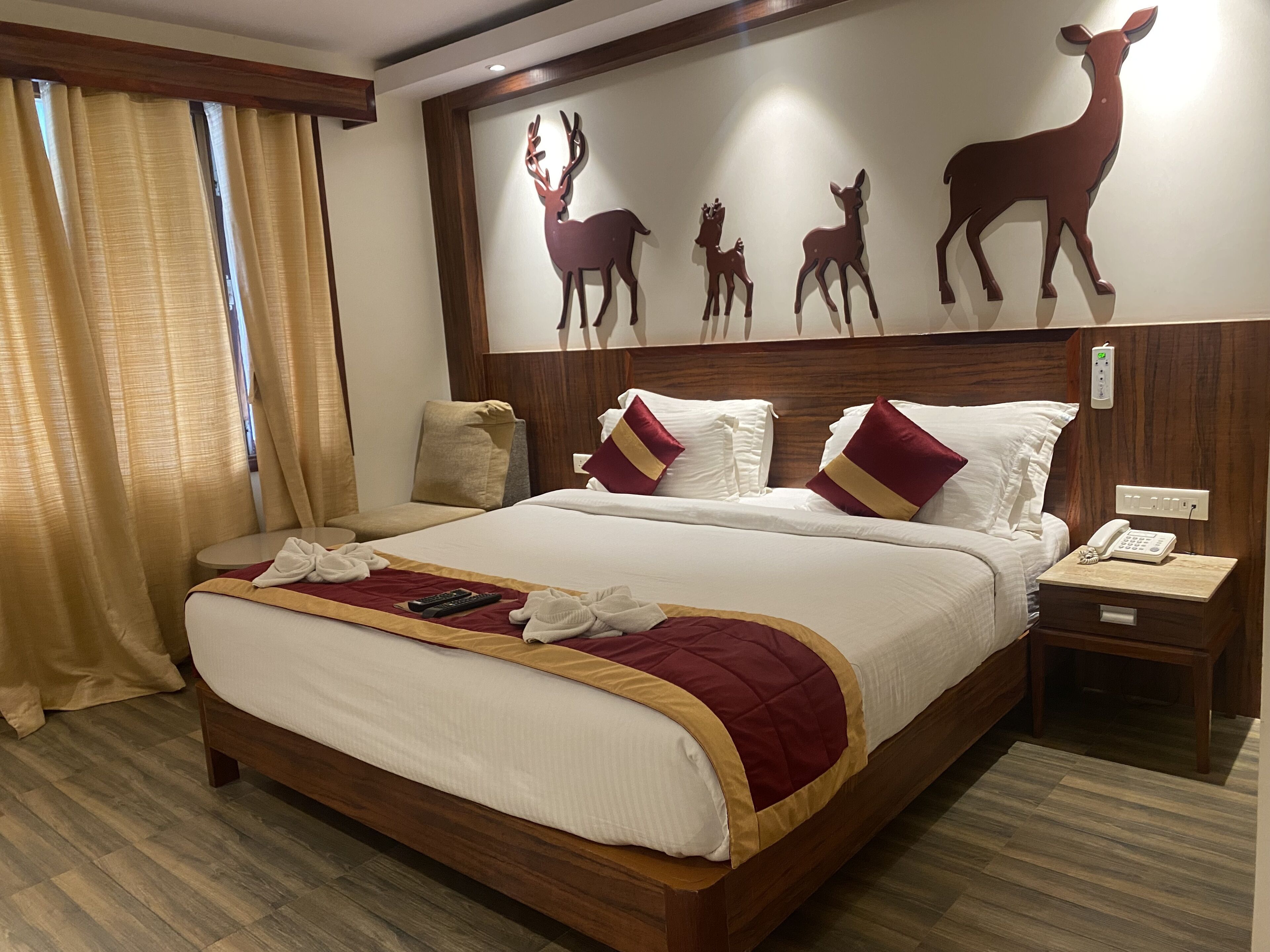 Una camera d'hotel con un letto grande, una testiera in legno e un'opera d'arte a parete raffigurante cervi.