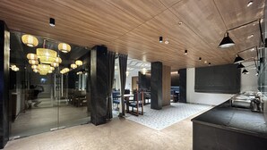Een modern interieur met een houten plafond, glazen scheidingswanden en een zithoek met tafels en stoelen.