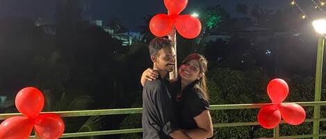 Um casal se abraçando sob uma decoração luminosa em formato de coração.
