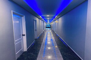 A long, narrow hallway with a marble floor and blue lighting.
