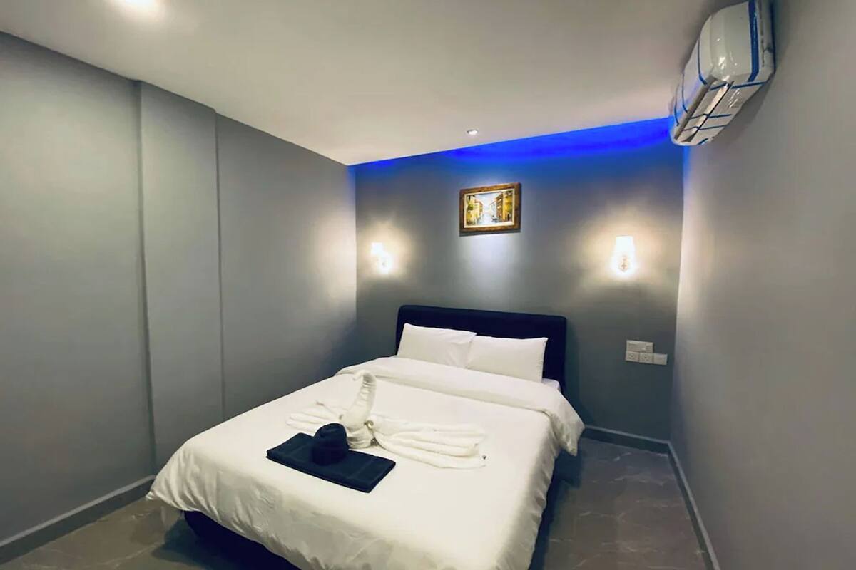 Una habitación de hotel con una cama, aire acondicionado de pared y un cuadro enmarcado.