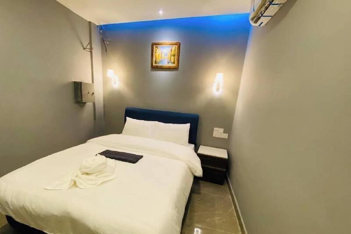 Una habitación de hotel con cama, mesita de noche, un cuadro en la pared y una bata sobre la cama.