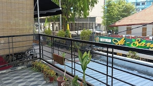 Ein Balkon mit Blumentöpfen, einem Geländer und Blick auf ein Restaurant namens Restoran A-Sari.