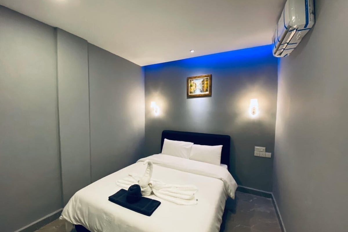 Ein Hotelzimmer mit einem Bett, einer Wandklimaanlage und einem gerahmten Bild an der Wand.