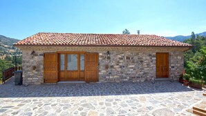 A stone building with a tiled roof, two wooden doors, and a stone-paved entrance. - Agriturismo Quercia Antica (Terranova di Pollino)