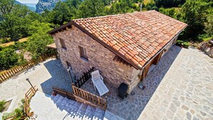 A stone building with a tiled roof, a paved courtyard, and a wooden fence. - Agriturismo Quercia Antica (Terranova di Pollino)