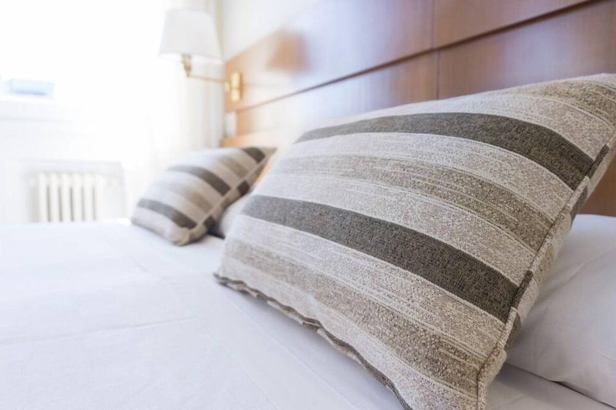 A bed with striped pillows and a wooden headboard.