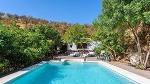A swimming pool with lounge chairs, surrounded by lush greenery and a hillside in the background. - La Casilla Guaro by Ruralidays (Málaga)