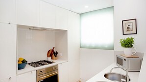 Une cuisine moderne avec des meubles blancs, une cuisinière à gaz, un évier et un four à micro-ondes.