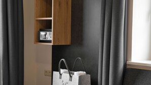 A room with a wooden shelf holding a telephone, a grey bag, and a grey curtain. - Landgasthof Hirschen (Hohentengen am Hochrhein)