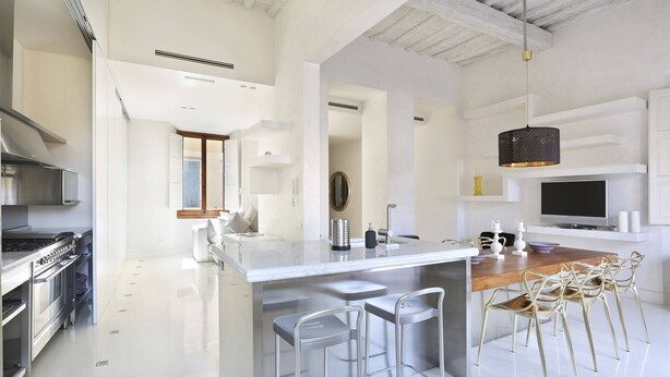 A modern kitchen with a large island, stainless steel appliances, and bar stools.