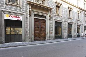 Un bâtiment portant l’enseigne « CONAD CITY », doté de grandes portes en bois et d’une façade en briques.