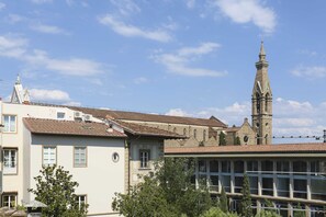 Un edificio histórico con una torre destacada y un edificio moderno con amplios ventanales.