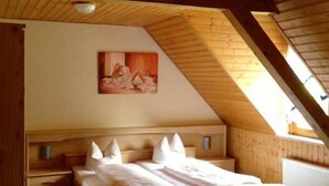 A bedroom with a sloped ceiling, a wooden bed, a nightstand, and a painting on the wall. - Hotel Saalestrand (Unterwellenborn)