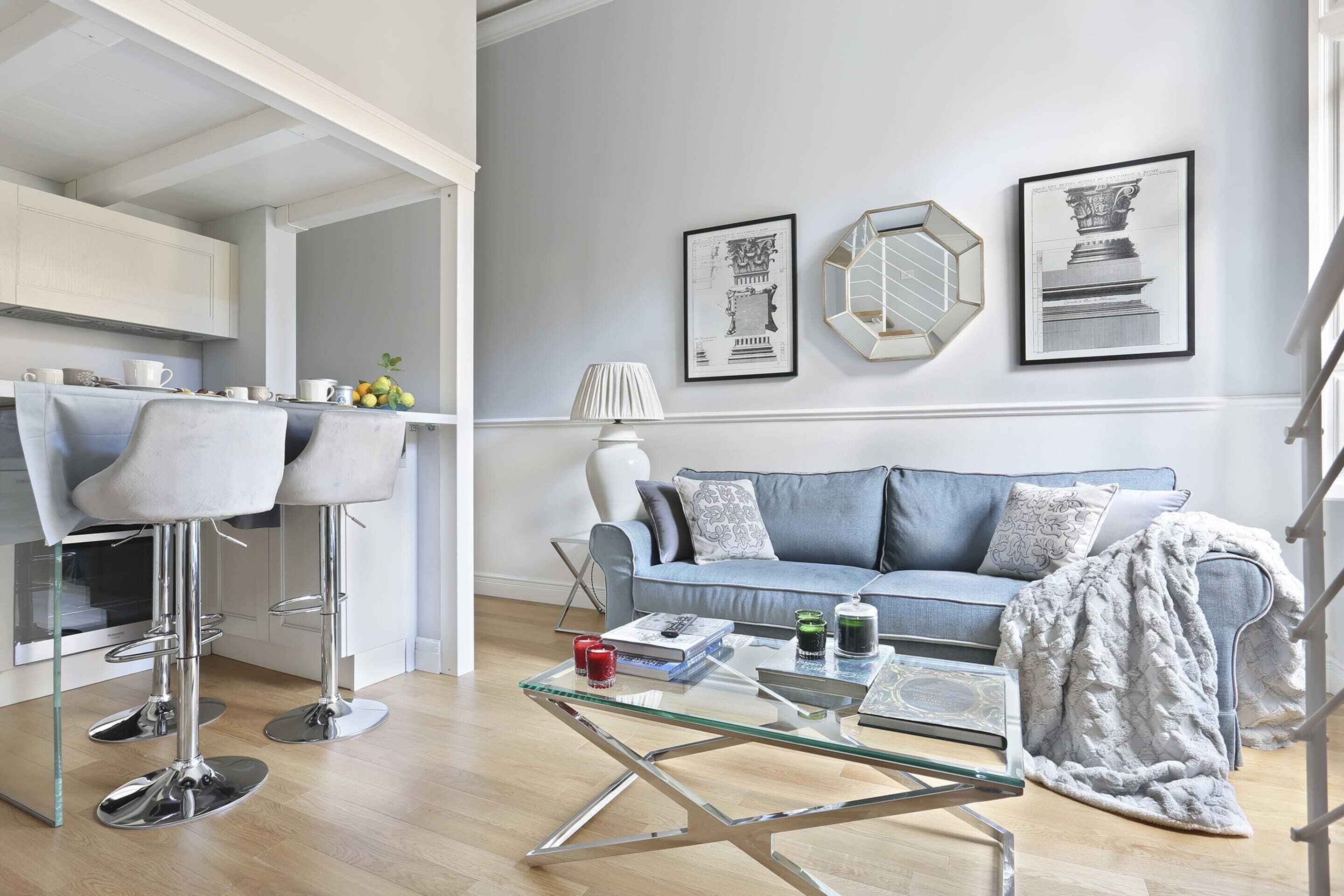Un salon moderne avec un canapé, une table basse en verre et deux tabourets de bar.