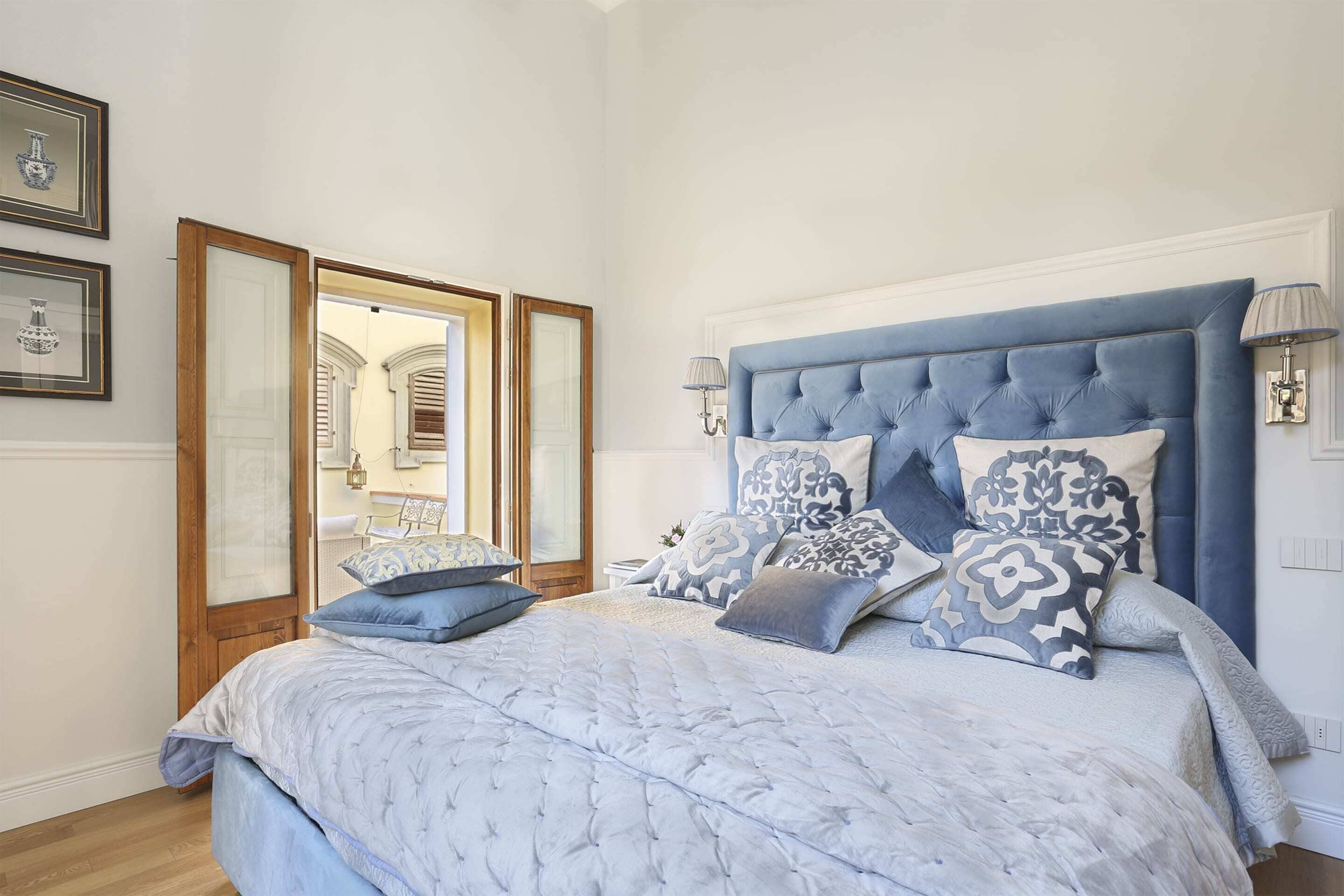 Une chambre à coucher avec un grand lit, une tête de lit bleue et un miroir.