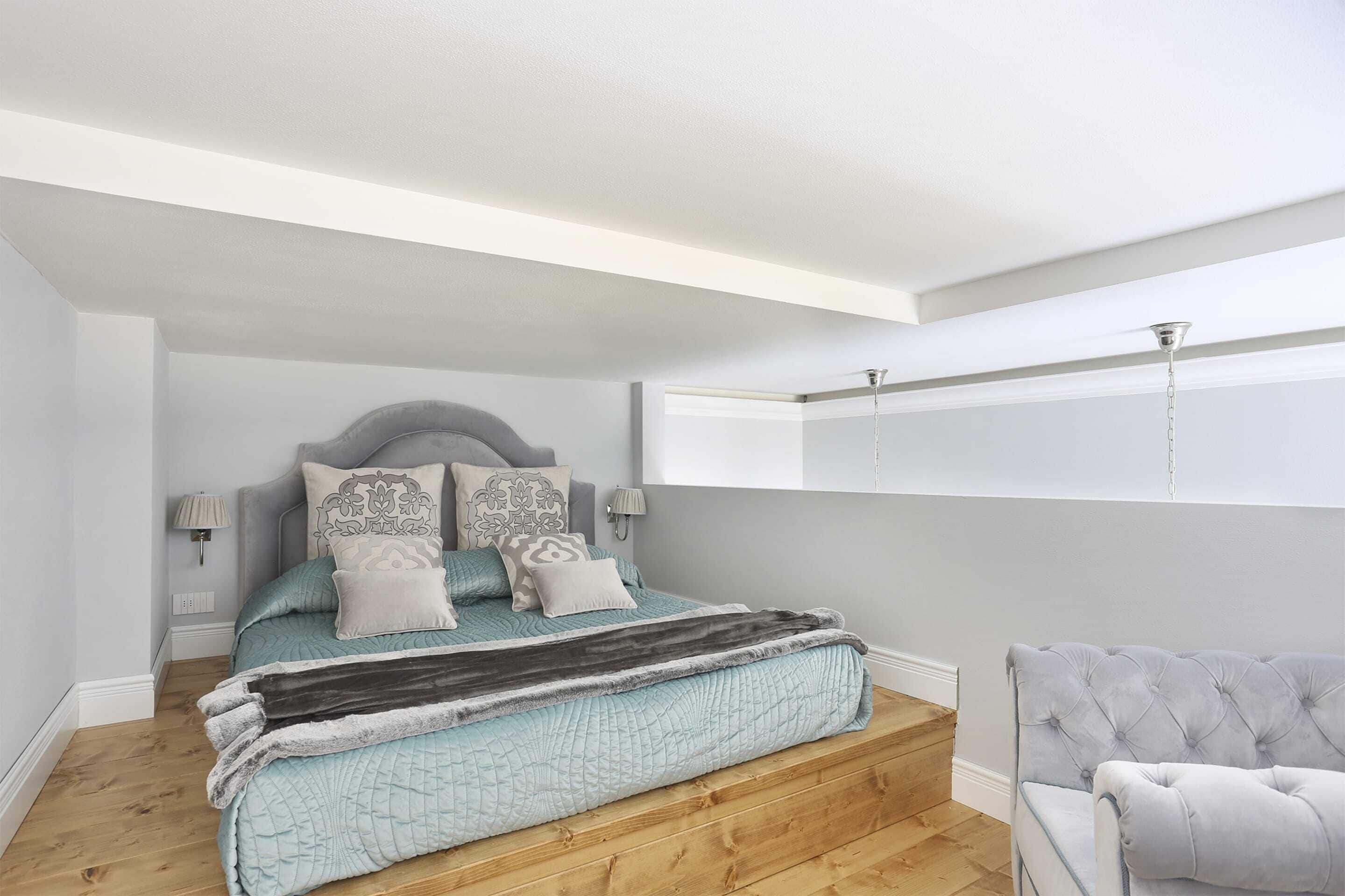 A bedroom with a bed, bedside lamps, a chair, and a window.