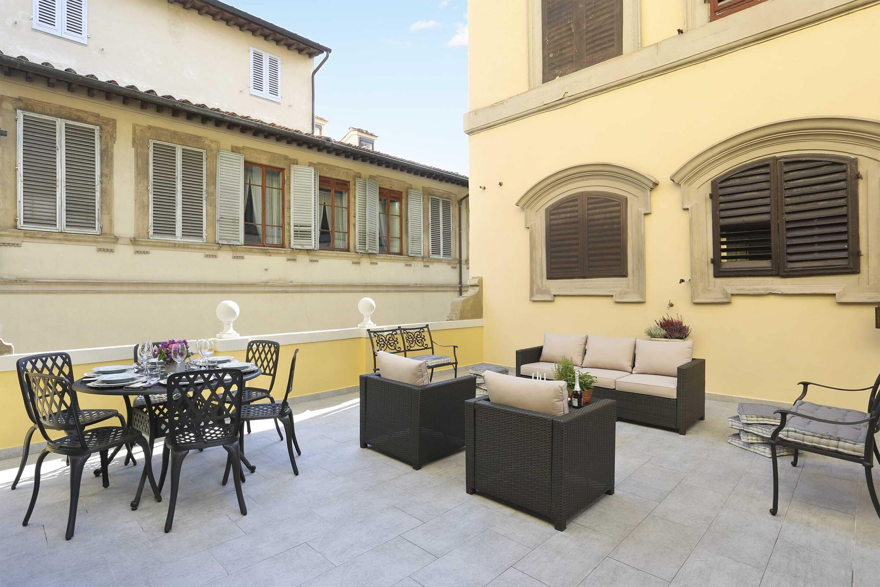 An outdoor patio with a round table, black wicker chairs, and a sofa.
