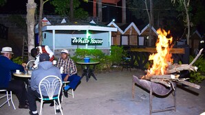 An outdoor dining area with a fire pit and tables. - Vienna Woods Holiday Inn Limited (Nakuru)