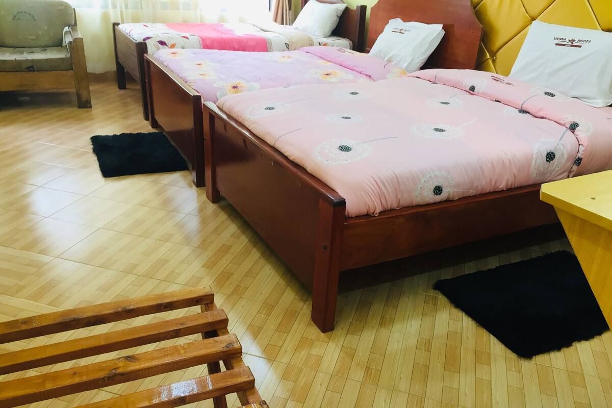 A bedroom with a wooden bed, a wooden chair, a small table, and a window with curtains.