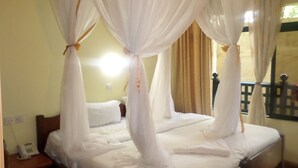 A room with a four-poster bed, white curtains, and a view of the outside. - Vienna Woods Holiday Inn Limited (Nakuru)