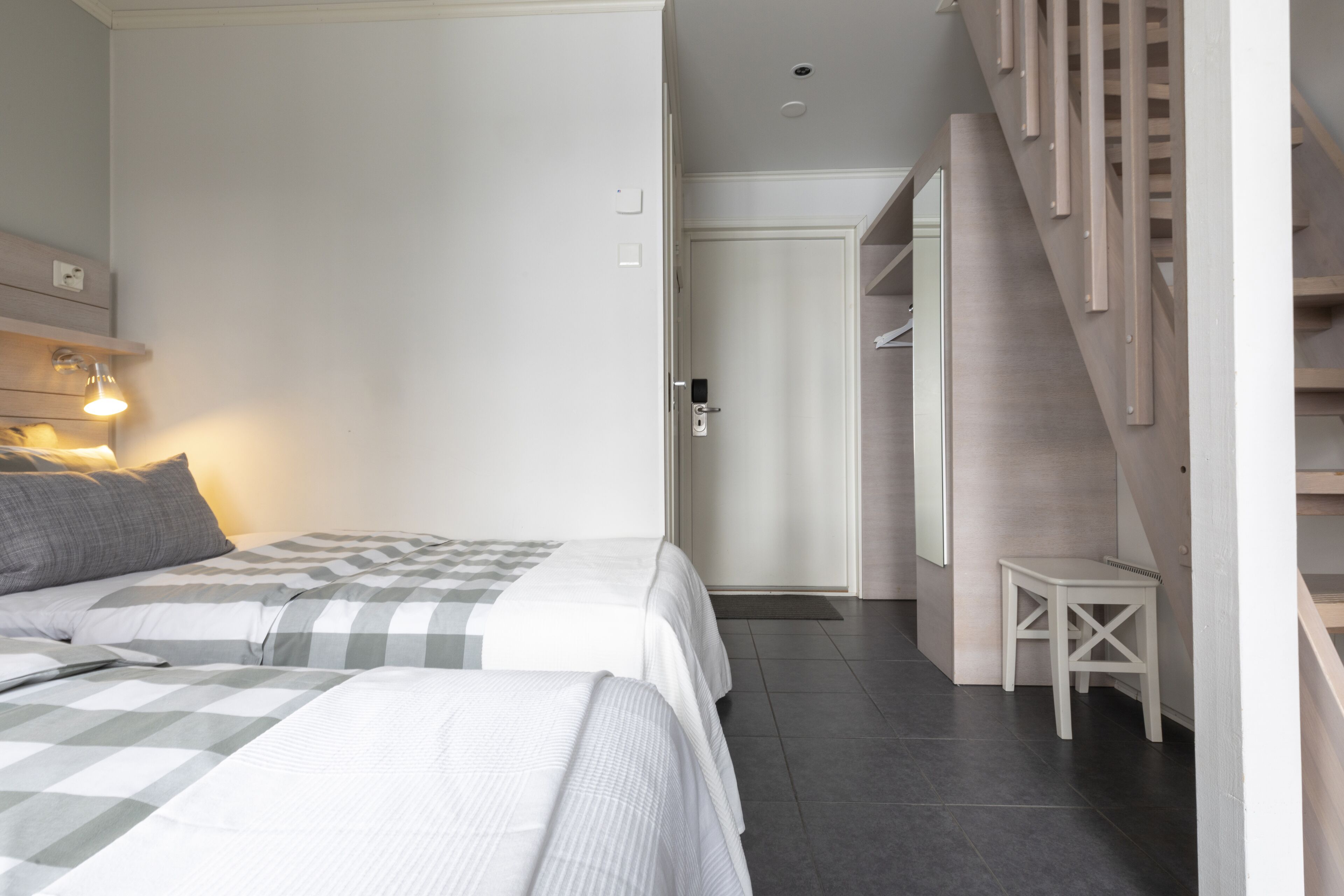A bedroom with two beds, a staircase, and a small table.