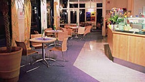 A restaurant with round tables and chairs, a counter with a display, and a purple carpeted floor. - Hotel beim Hirschen (Merzhausen)