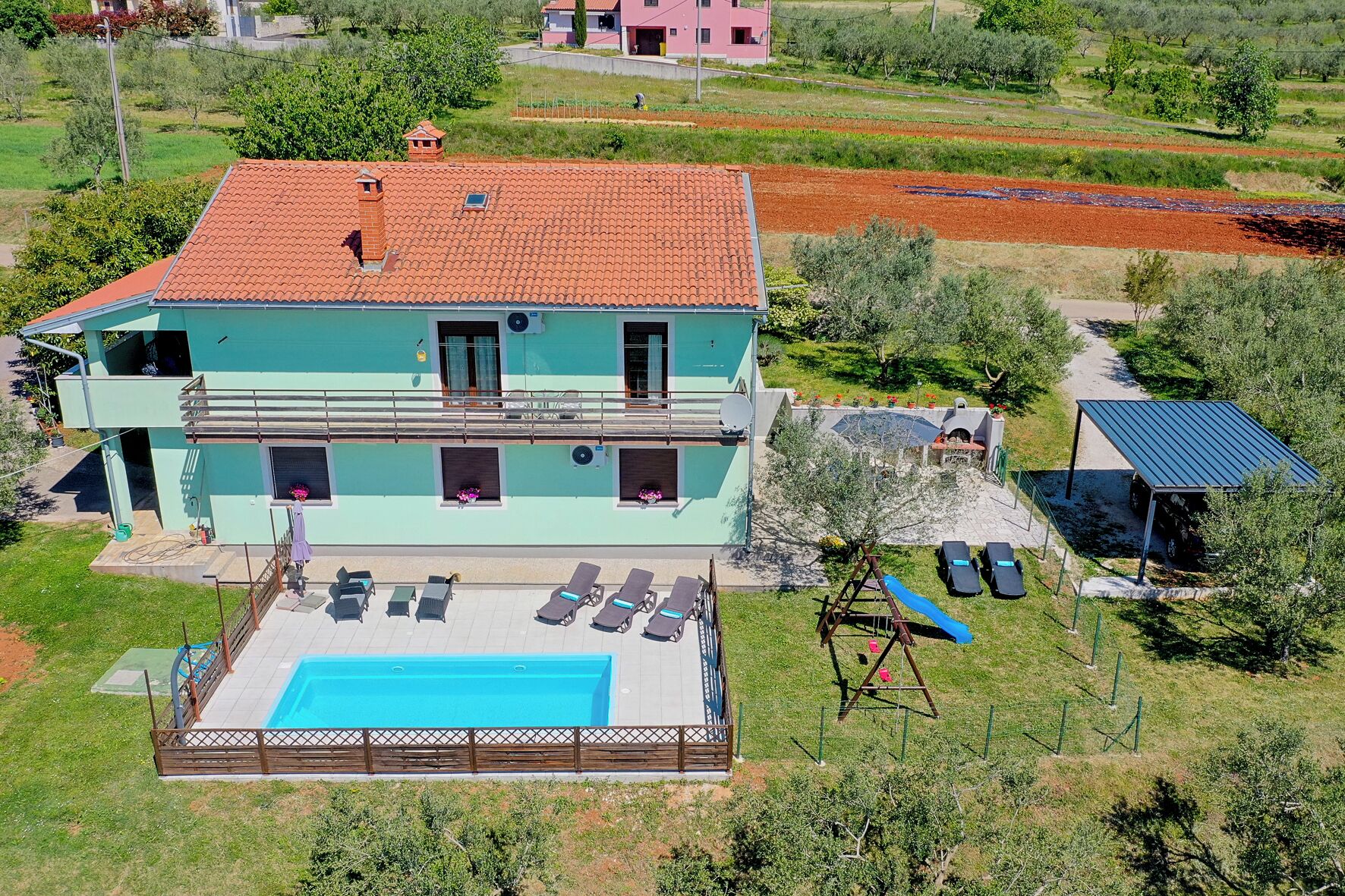 Et toetagers hus med swimmingpool, overdækket terrasse og have.