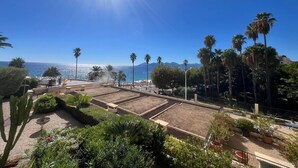 Un jardin sur le toit offrant une vue sur la mer et les montagnes, entouré de palmiers et de diverses plantes.