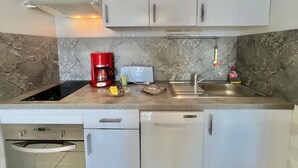 Une cuisine moderne avec des meubles gris, une machine à café rouge, un grille-pain et un lave-vaisselle.