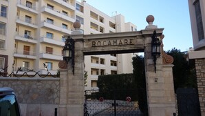 Un arc en pierre portant l’inscription « ROCAMARE » mène à un immeuble à plusieurs étages doté de balcons.