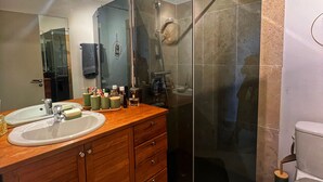 Ein modernes Badezimmer mit einer gläsernen Duschkabine, einem Holzkosmetikschrank und einem großen Spiegel.