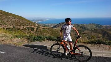 Ein Radfahrer steht neben seinem Fahrrad an einer Straße mit einem schönen Ausblick auf eine Küstenlandschaft.