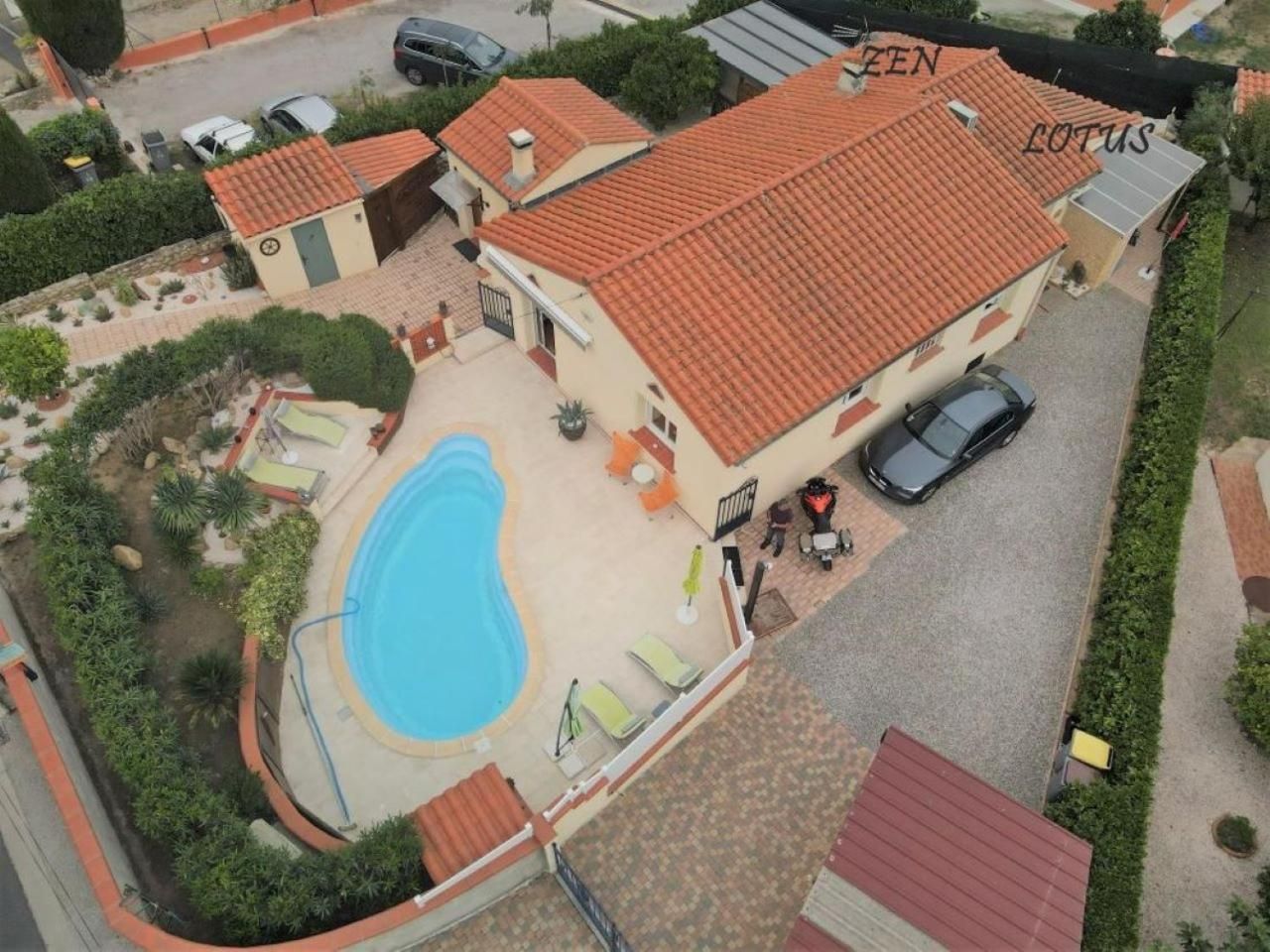 Ein zweistöckiges Gebäude mit Swimmingpool, Sitzgelegenheiten im Freien und einem Auto auf der Auffahrt.