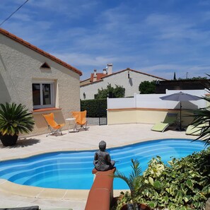 A swimming pool with a statue in the foreground, surrounded by outdoor seating and potted plants. - La Picholine (Sorede)