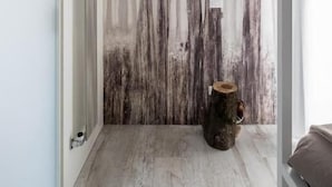 Una habitación moderna con piso de madera, un panel de madera grande en la pared y un taburete de madera pequeño.