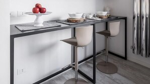 Una cocina moderna con una isla central, taburetes de bar y un espejo grande sobre la encimera.