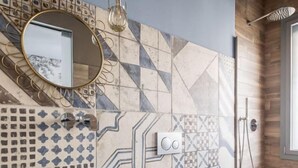 Un baño moderno con un lavamanos grande tipo recipiente, tocador de madera y zona de ducha.