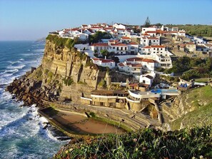 Un pueblo costero con edificios blancos, un acantilado rocoso y una playa.