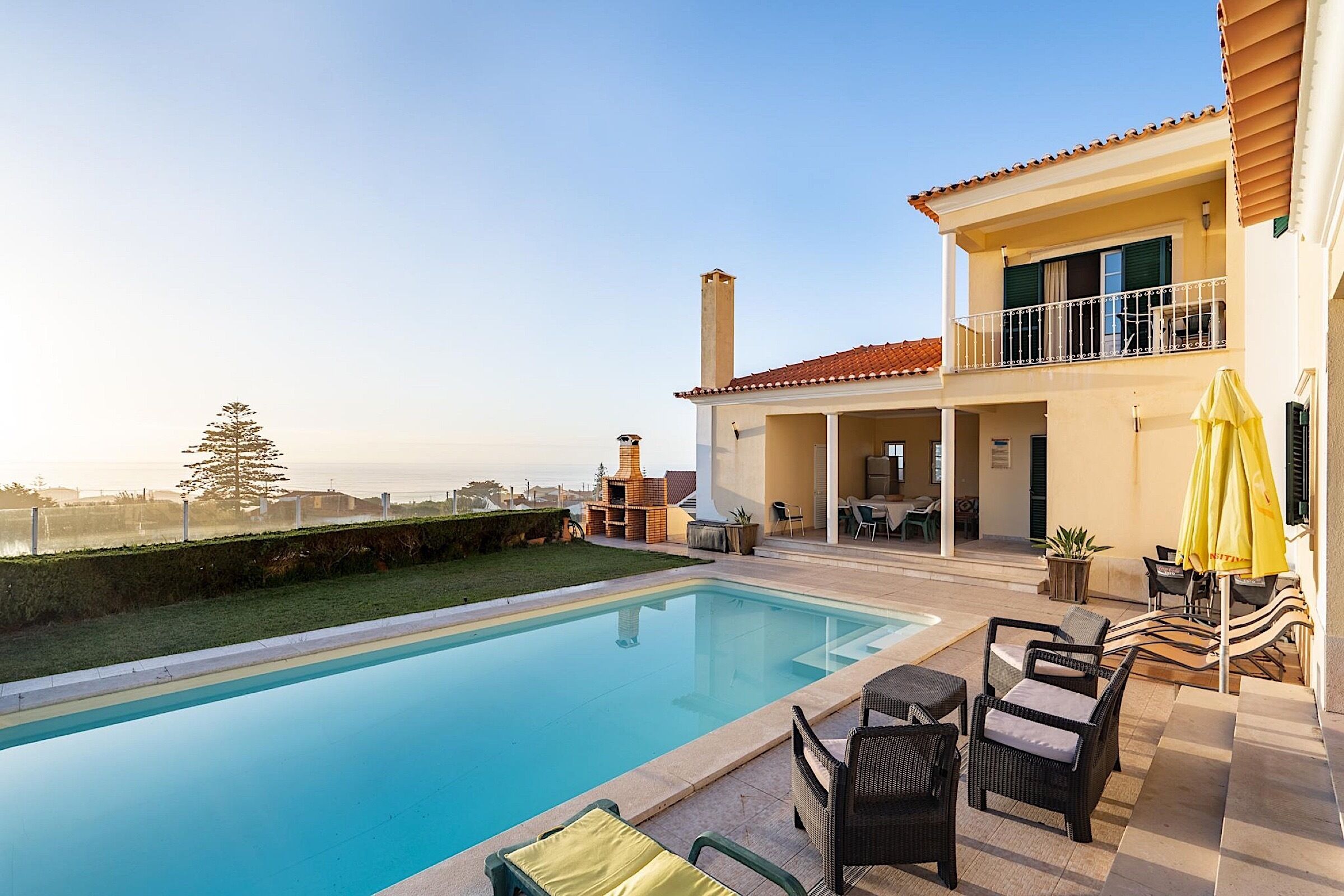 A swimming pool with outdoor furniture, a covered patio, and a view of the city.
