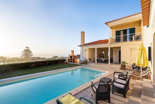 Una piscina con mobiliario exterior, un porche cubierto y vistas a la ciudad.
