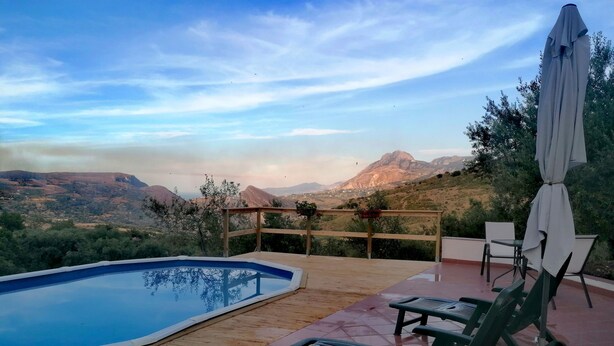 Un espace piscine doté d’une terrasse en bois, d’une petite piscine et offrant une vue sur les montagnes.