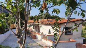 Une maison à deux étages, avec un toit recouvert de tuiles, un balcon et un escalier menant à l’étage supérieur.
