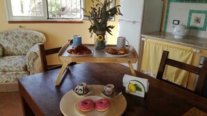 Un coin repas avec une table en bois, un canapé à motifs floraux et un vase rempli de fleurs.