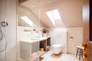 A modern bathroom with a glass shower enclosure, a white sink, and a toilet. - Landhaus Christl am See (Bad Wiessee)