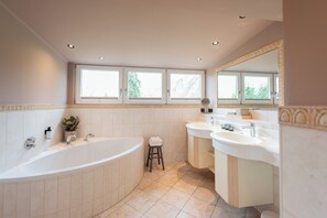 A modern bathroom with a freestanding bathtub, two sinks, and a large mirror. - Landhaus Christl am See (Bad Wiessee)