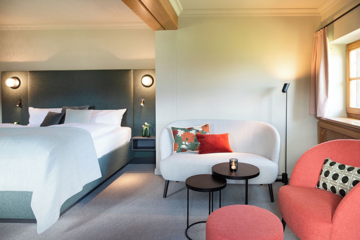 A hotel room with a bed, a sofa, a small table, and a nightstand.