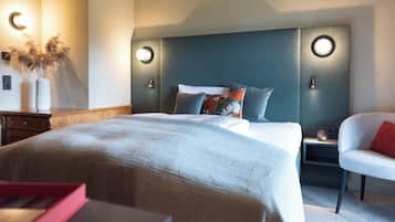 A neatly arranged bedroom with a large bed, bedside tables, a chair, and wall-mounted lighting.